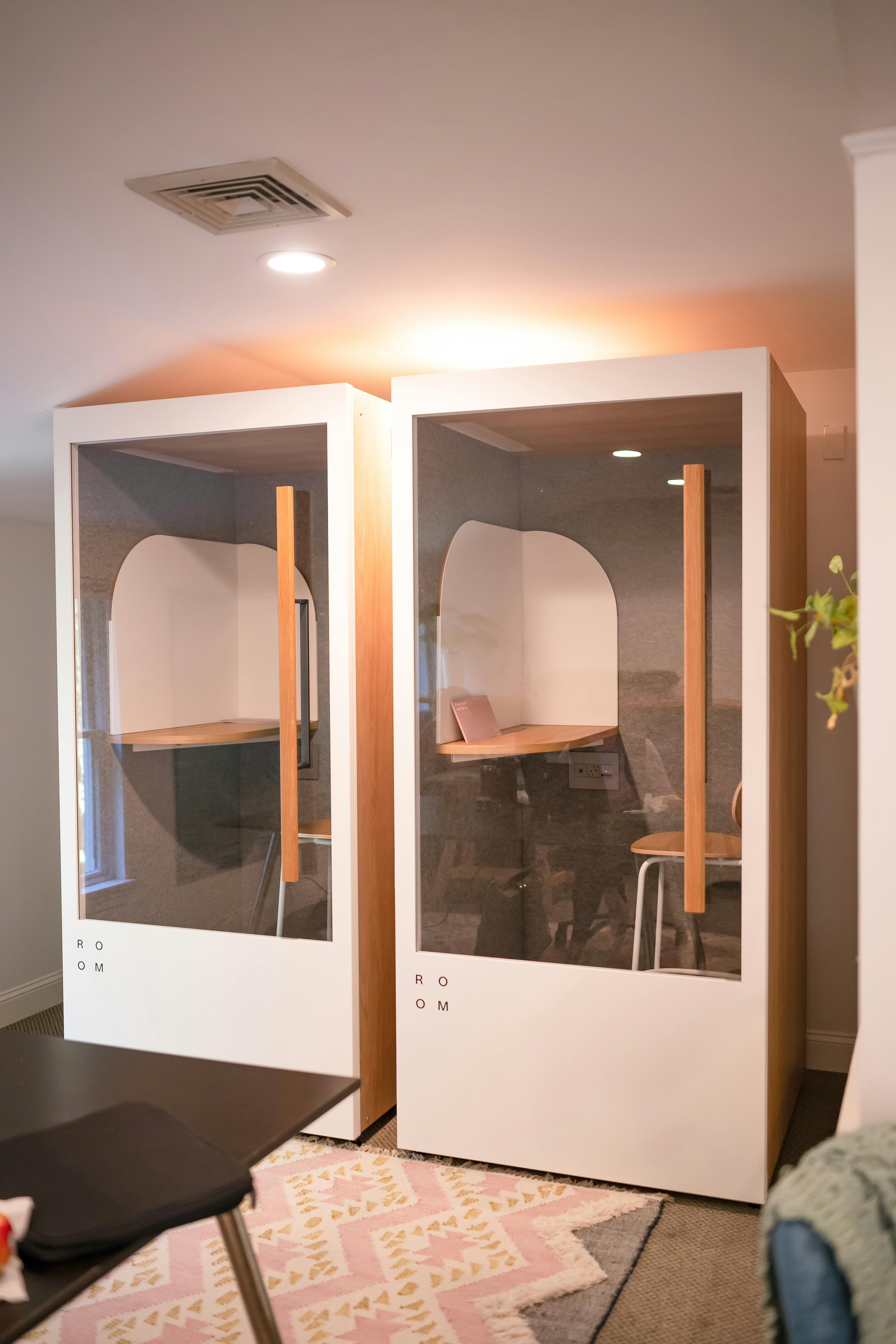 Two modern phone booths with glass fronts and wooden interiors