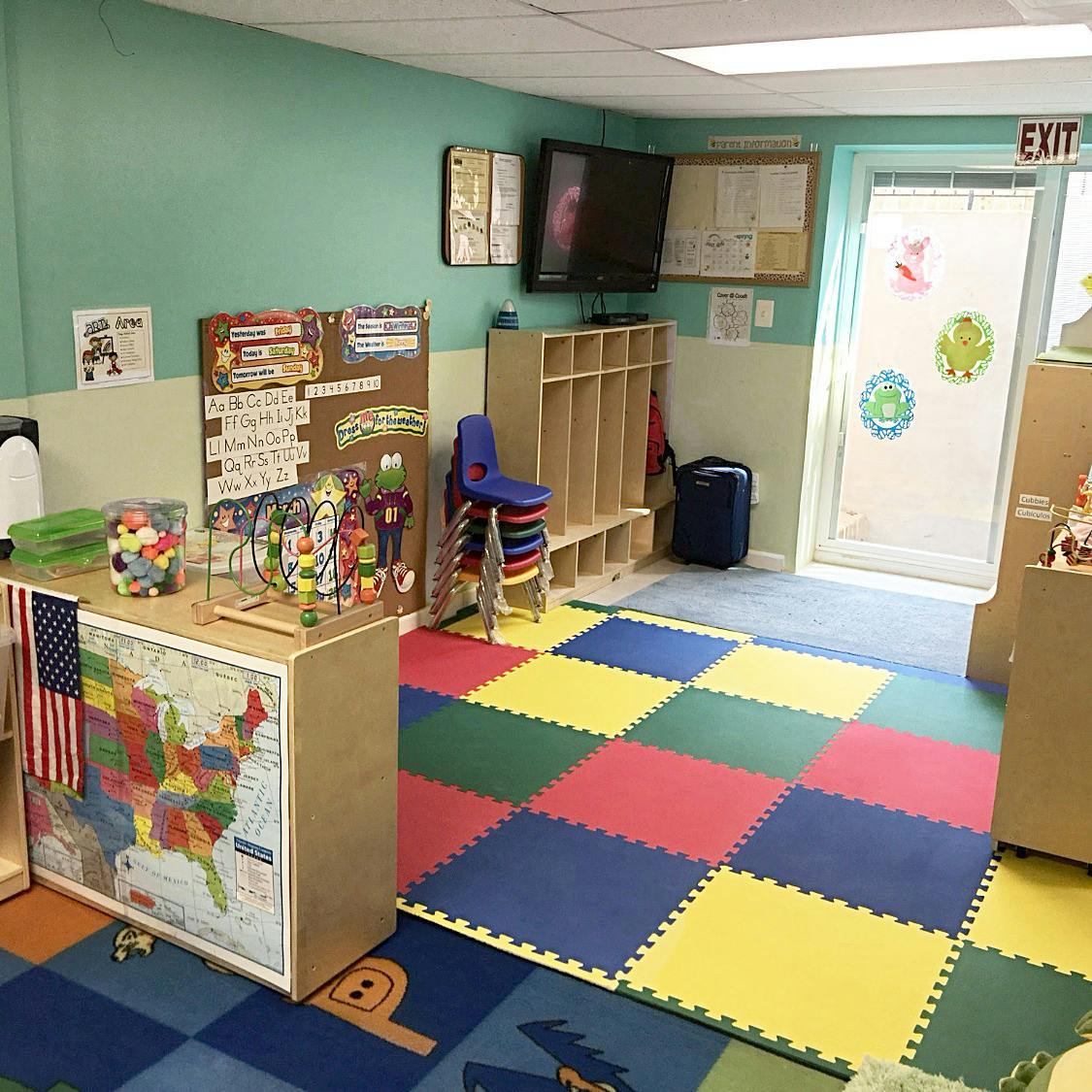 Classroom with colorful floor mats and an exit sign above a door
