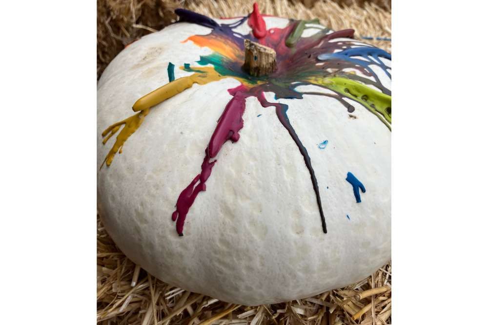 White pumpkin with melted crayon wax dripping down the sides