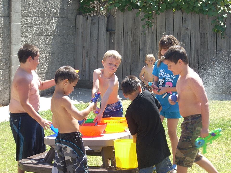 Children playing with water guns and buckets outdoors