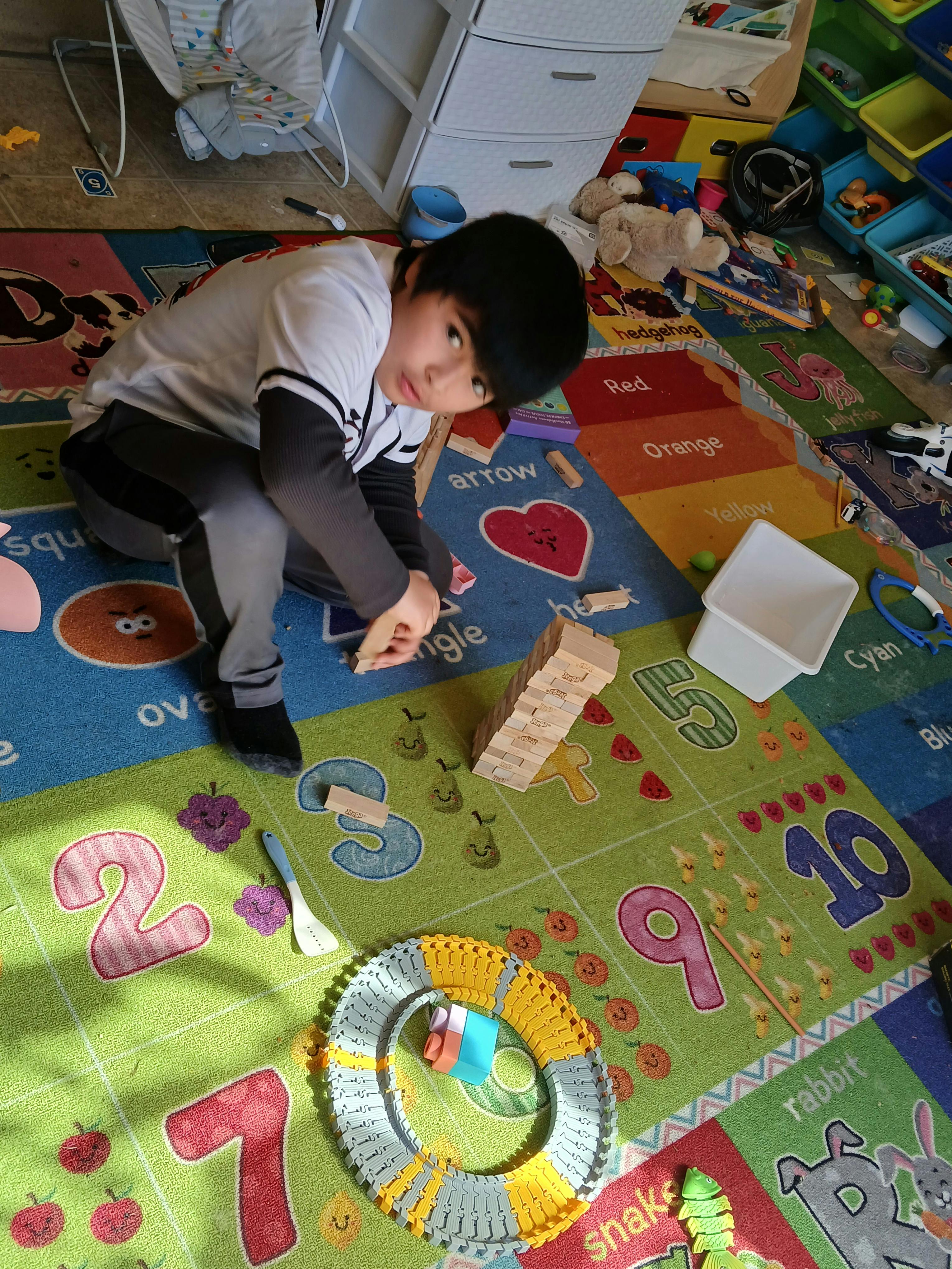 Child sitting on a colorful playmat, playing with building blocks