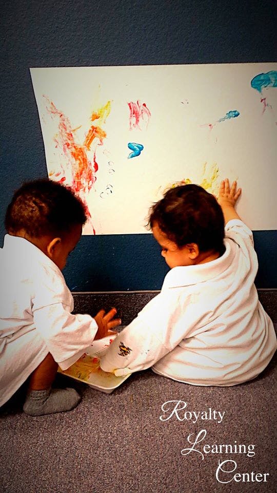 Two children finger painting on a large sheet of paper