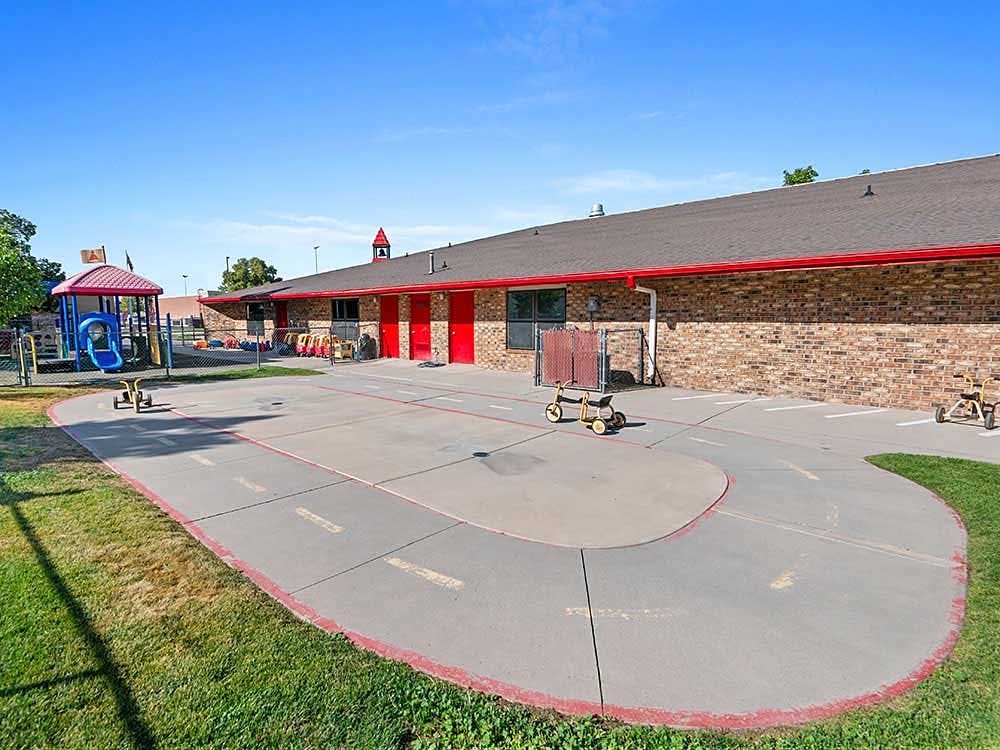 Outdoor play area with a painted road course and a playground structure
