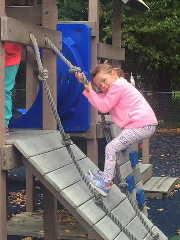Child climbing a rope ladder on a playground structure
