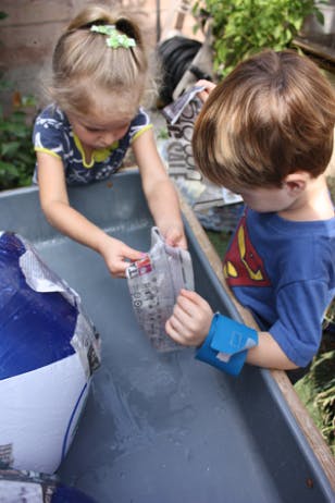 Two children playing with water in a trough