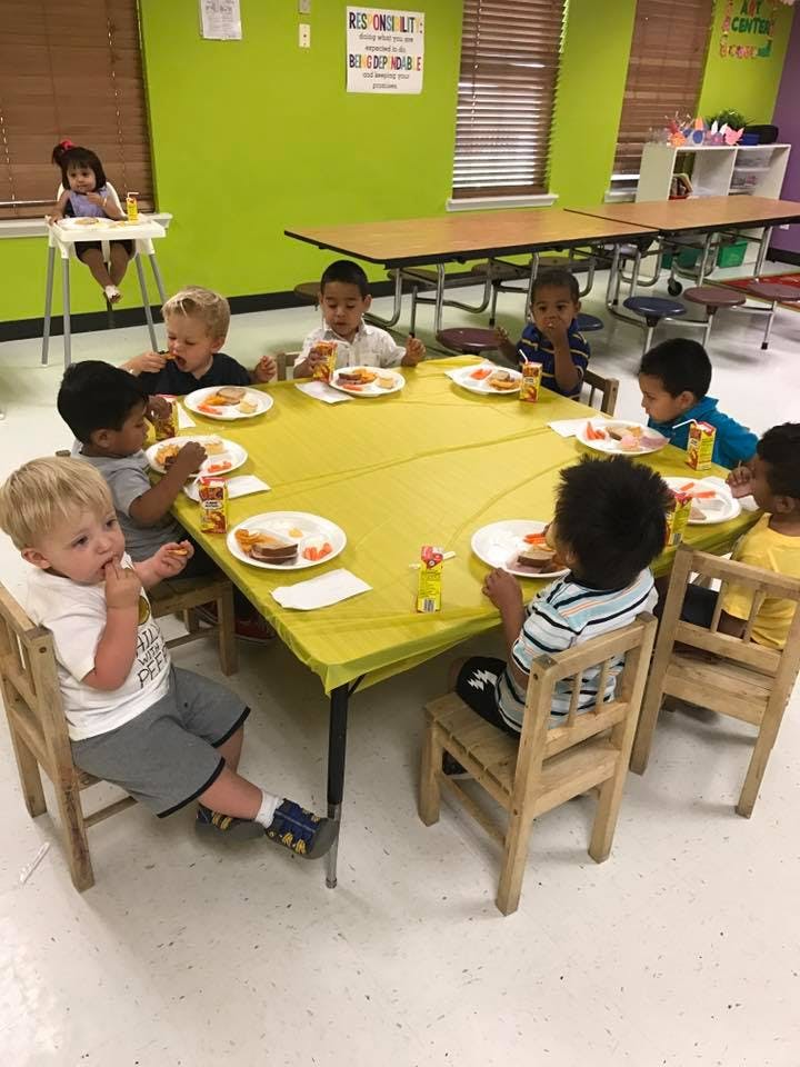 Children eating at a table in a classroom