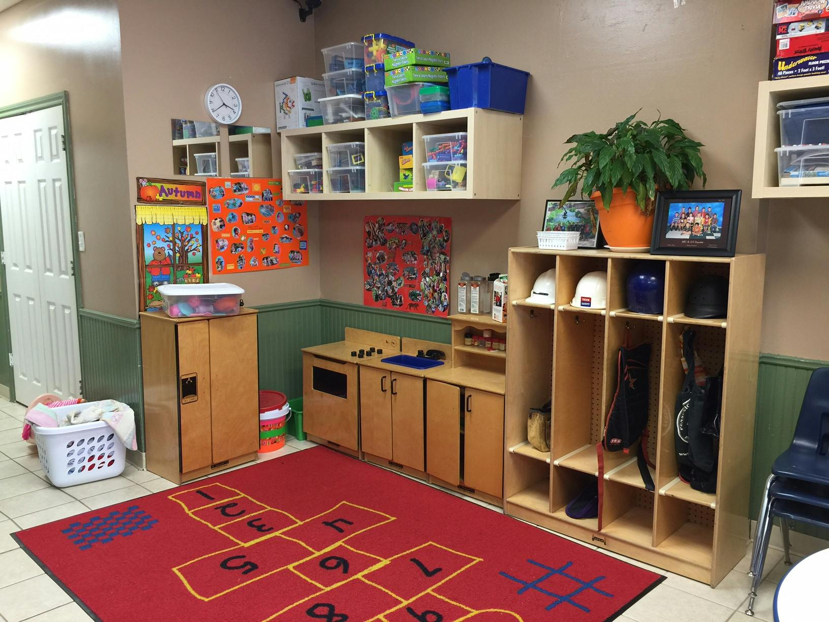 Playroom with red hopscotch rug, wooden cabinets, and shelves with toys