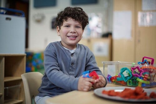 Child sitting at a table with toys and playdough