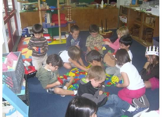 Children playing with colorful blocks on the floor in a classroom