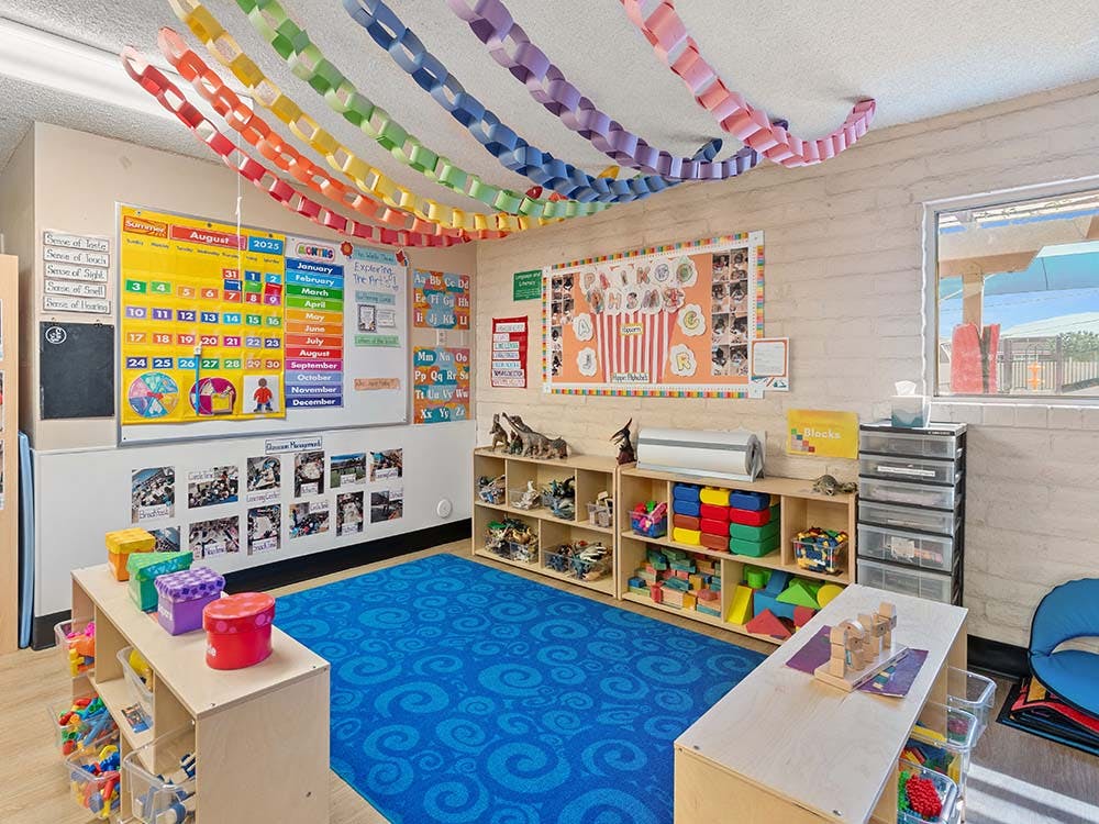 Colorful classroom with educational posters, toys, and blue carpet