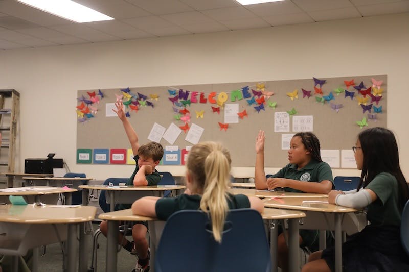Children in a classroom raising their hands