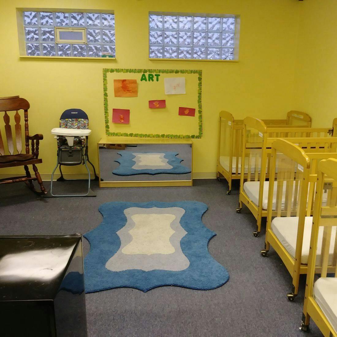 Nursery room with multiple cribs, a high chair, and an art display