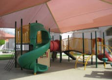Playground with slides and climbing structures under a shade canopy