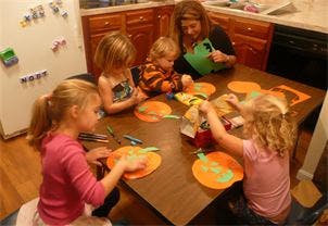 Adult and four children making crafts at a table