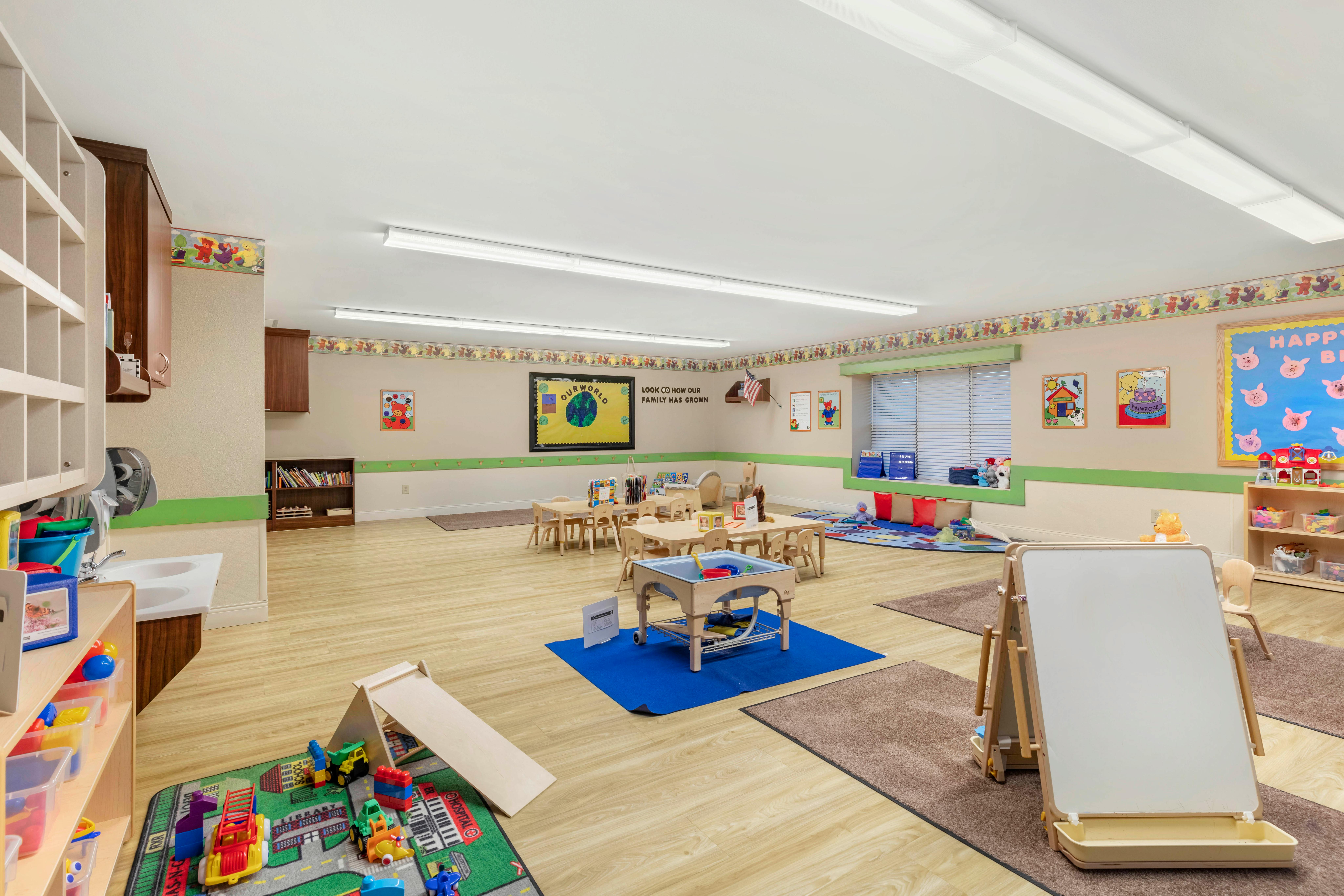 A colorful empty classroom with small tables and play areas