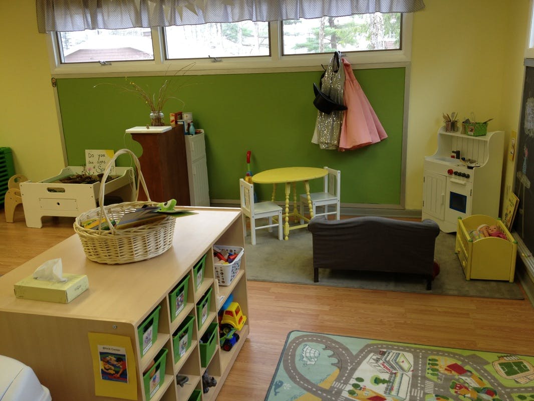 A classroom with small tables, chairs, and storage units