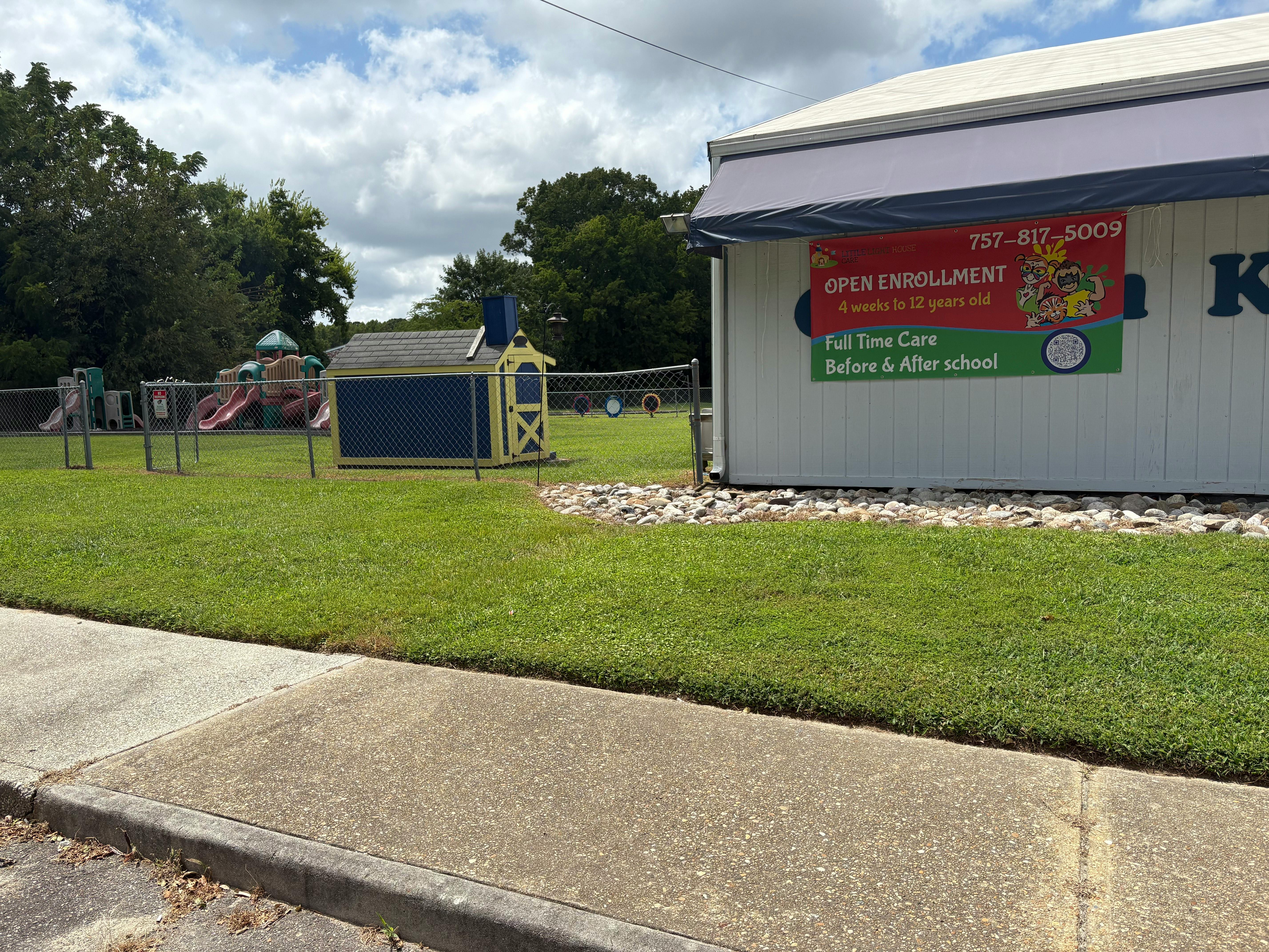 Building with a sign for "Open Enrollment" next to a playground