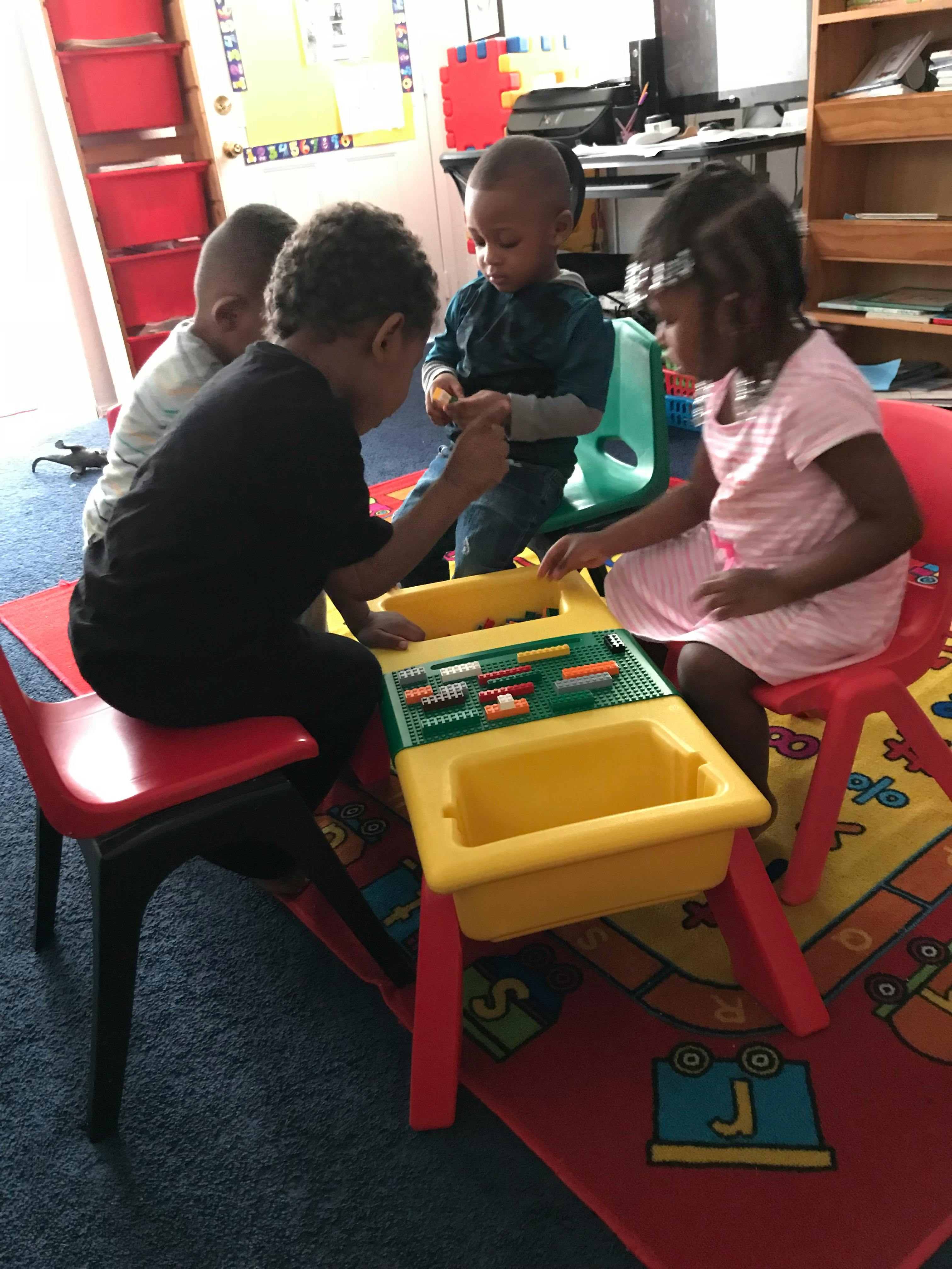 Children sitting at a plastic table playing with building blocks