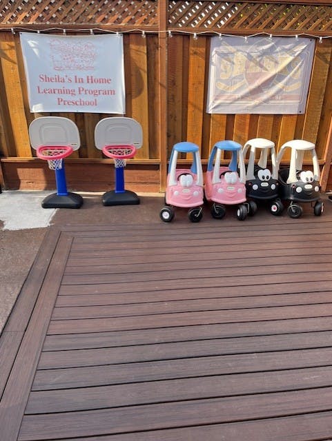 Two toy basketball hoops and four toy ride-on cars on a deck