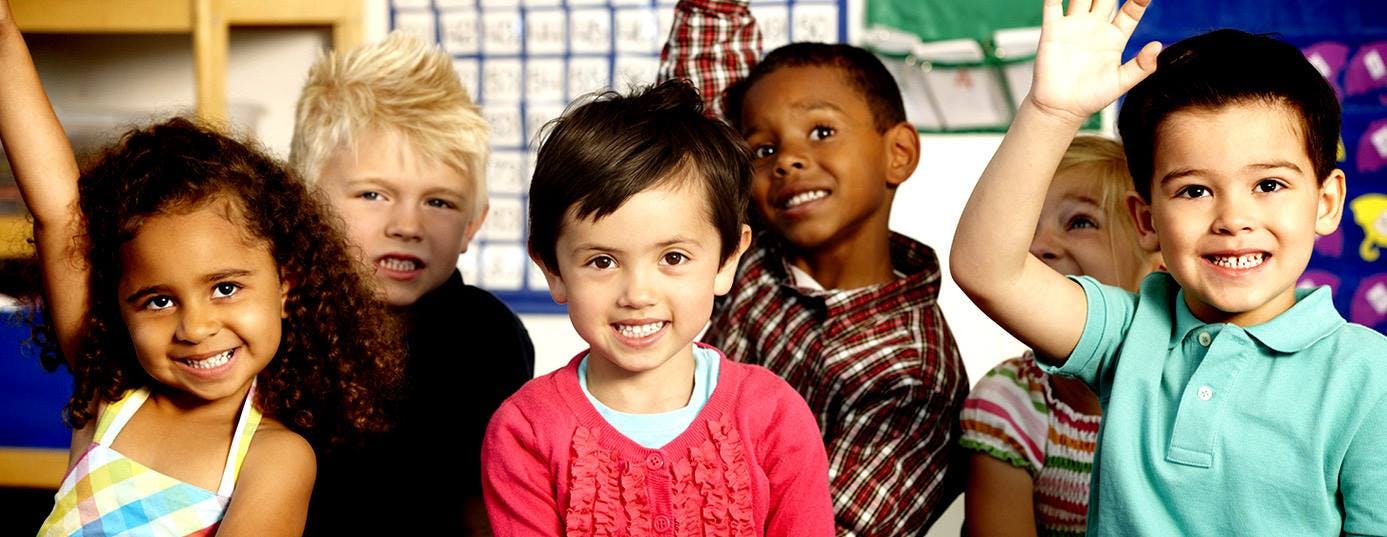Group of children smiling, one child raising a hand