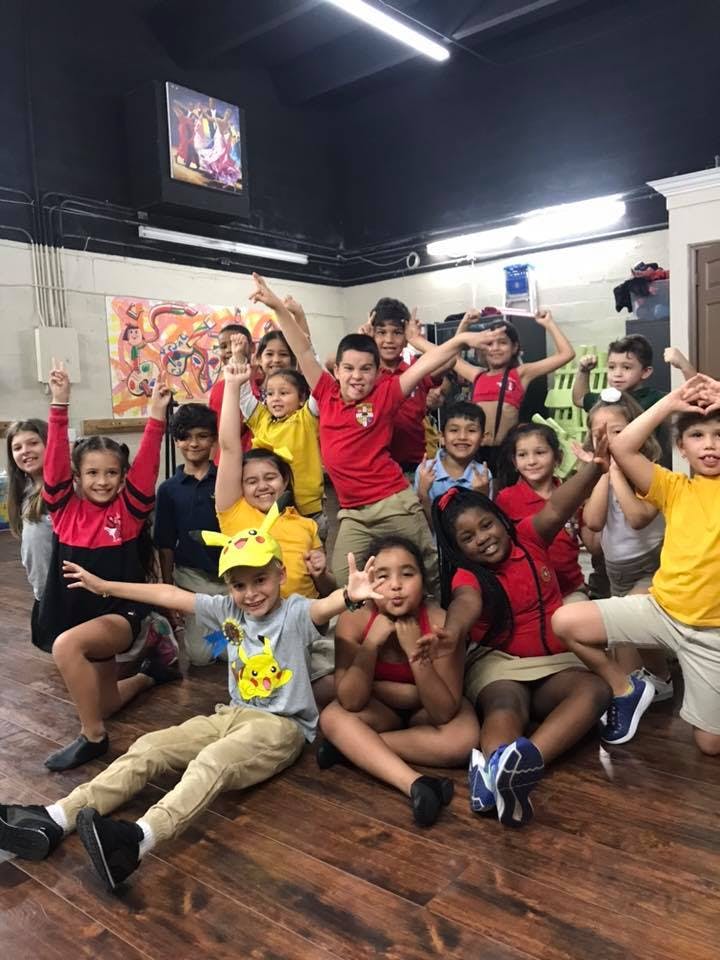 Group of children posing with arms raised and hands raised