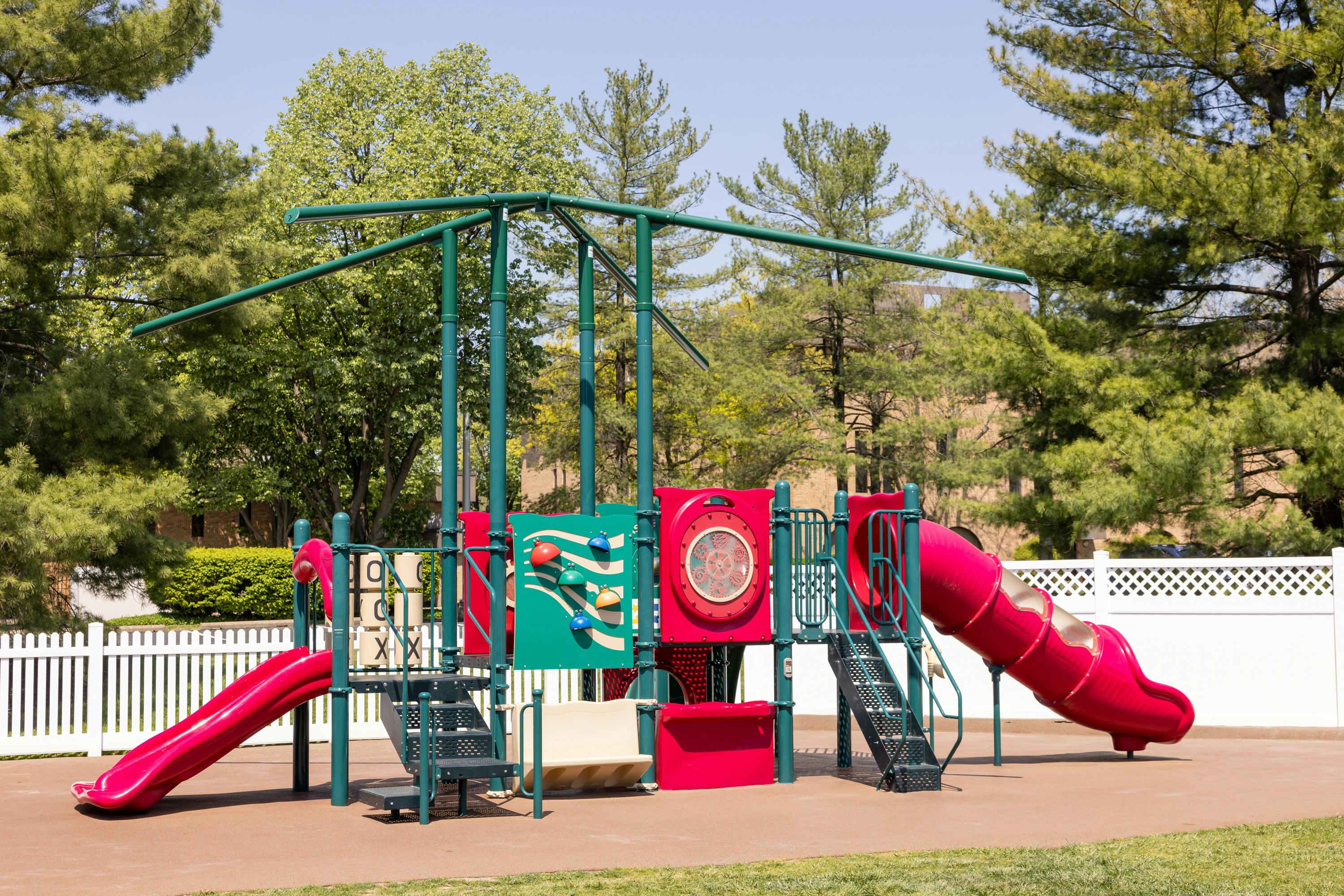 Playground with red slides and green climbing structures