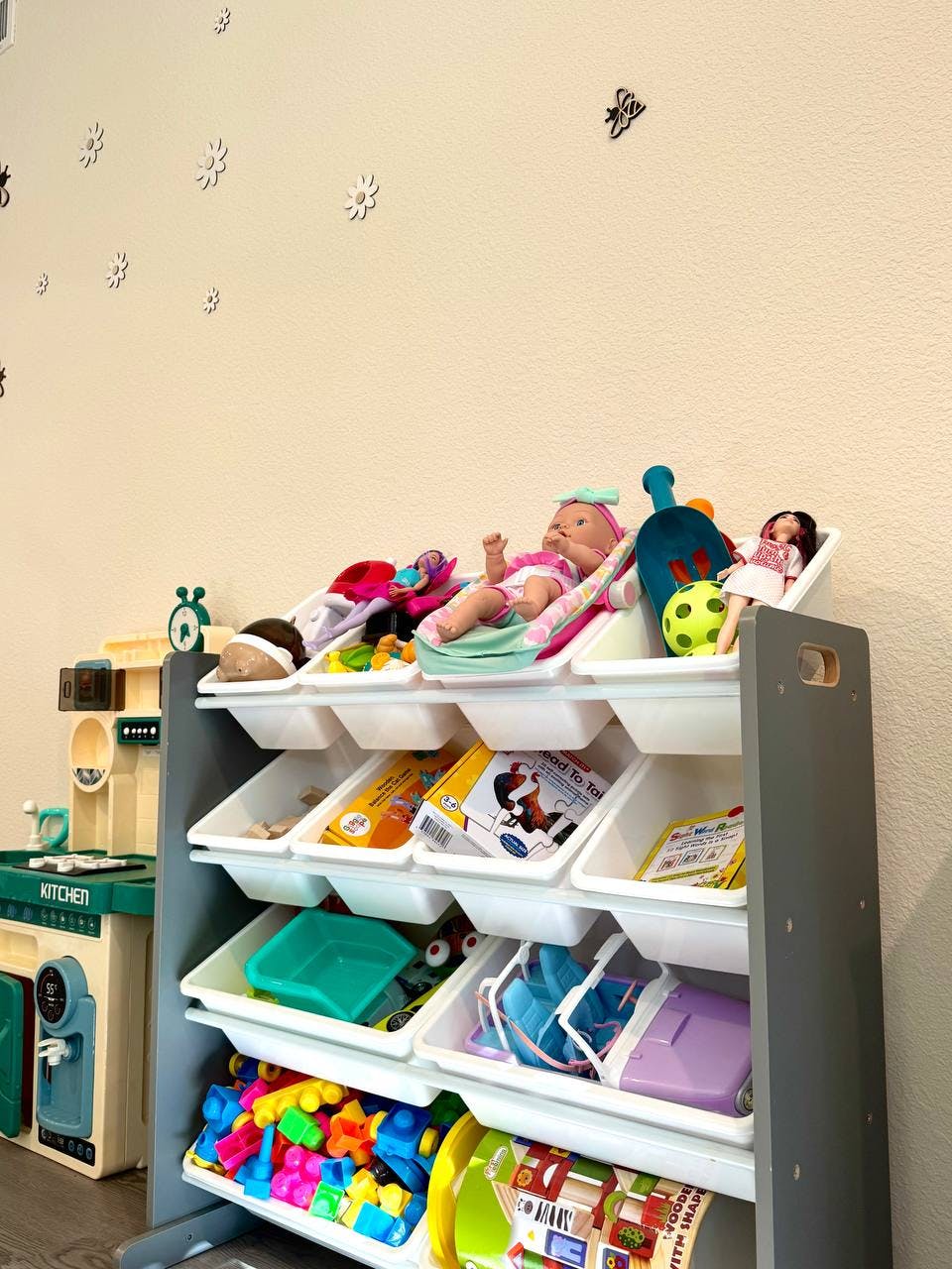 Toy storage unit with dolls and various toys in white bins