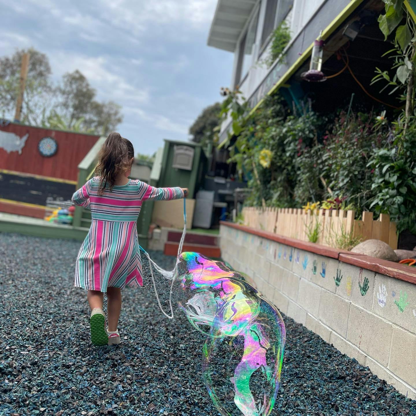 Child making a large bubble with a bubble wand