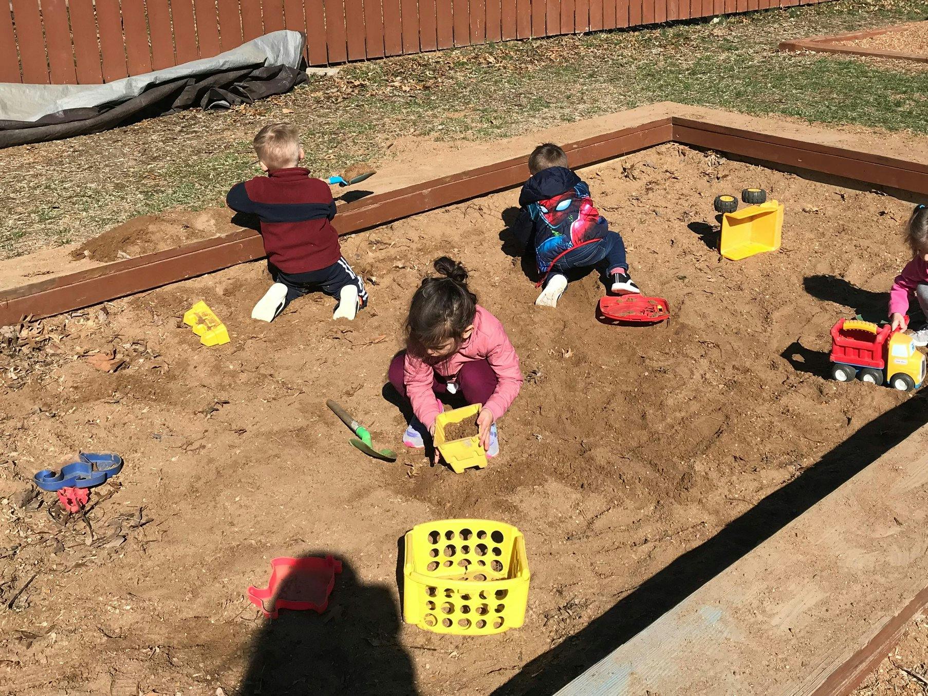 Children playing in a sandbox with toys