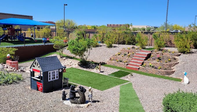 Outdoor play area with a small playhouse, artificial turf, and a shaded playground