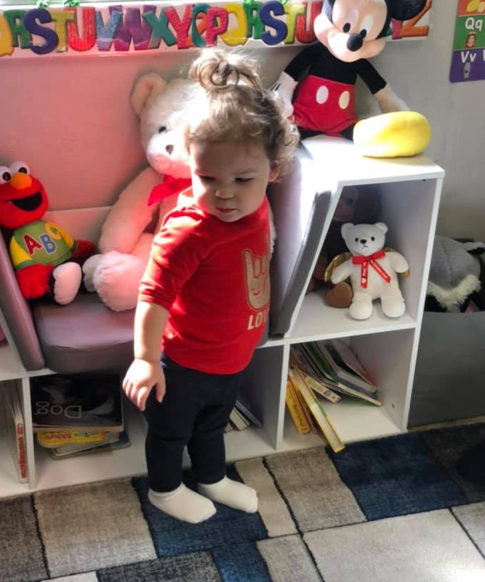 Child standing in a room with toys and shelves