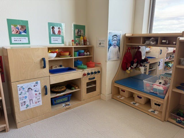 Play kitchen and wooden shelving unit with toys in a classroom