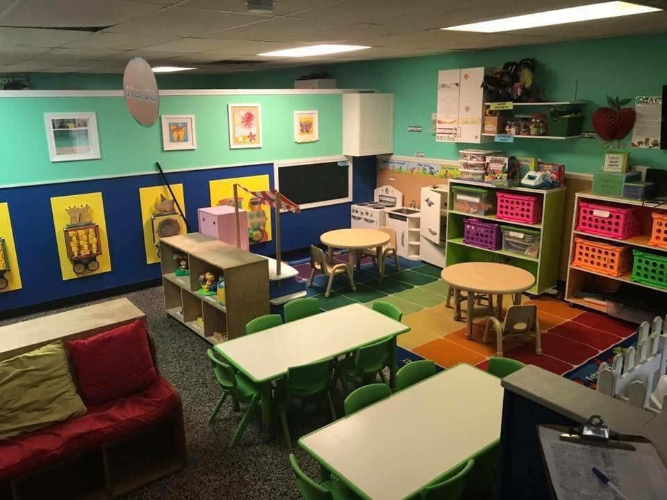 A colorful classroom with small tables, chairs, and storage shelves