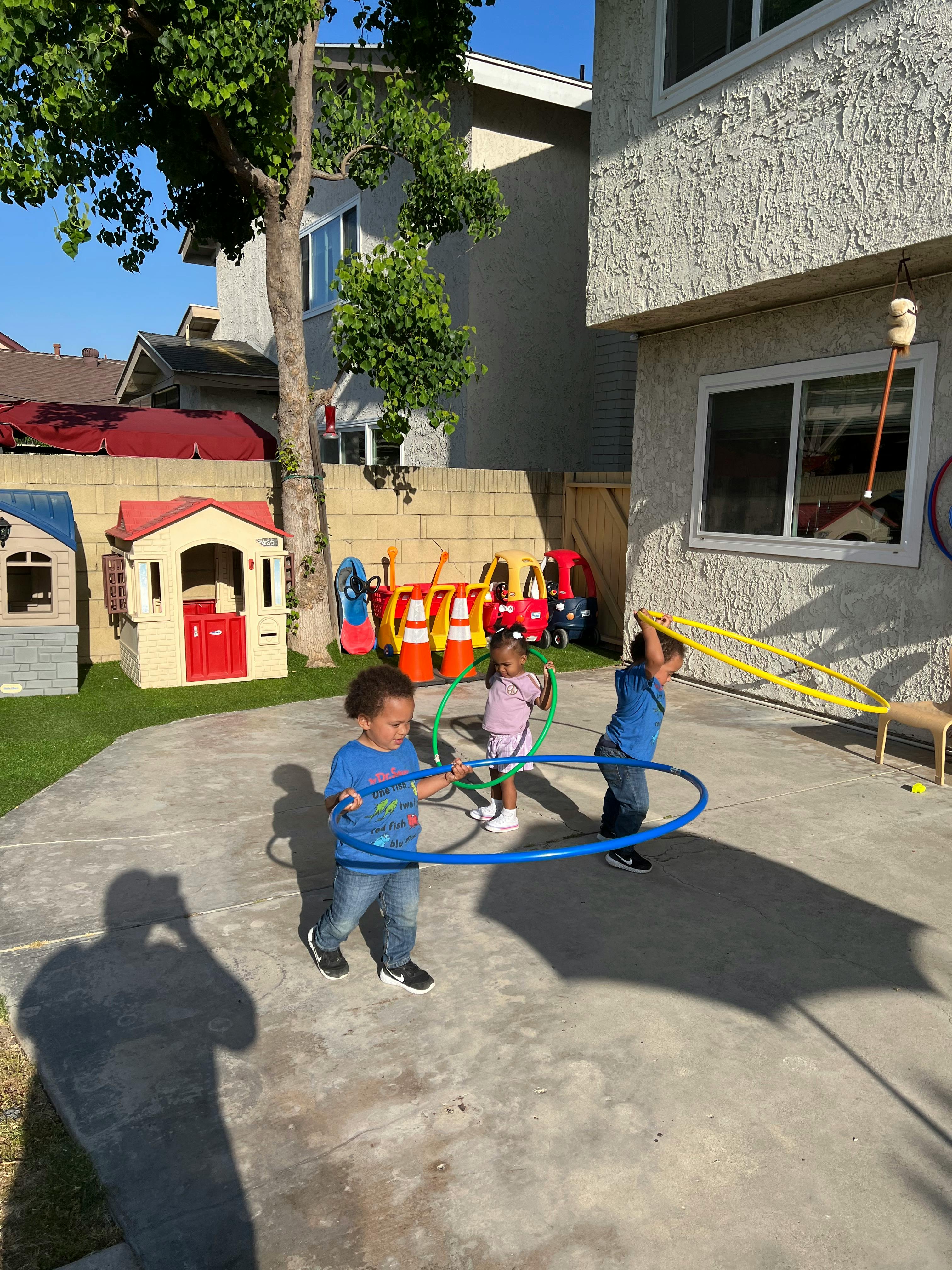 Three children playing with hula hoops outdoors