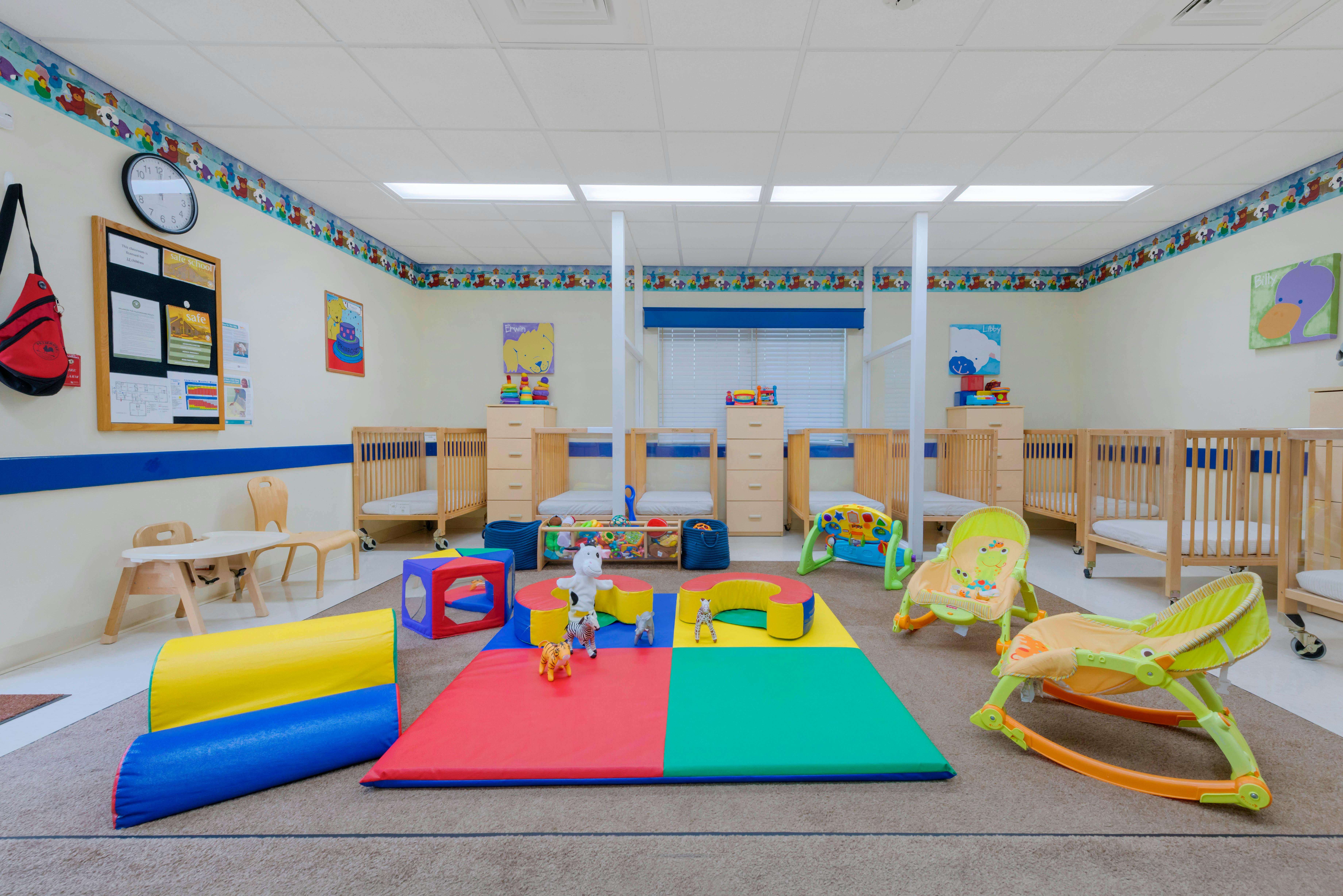 Baby room with multiple cribs, play mats, and infant chairs
