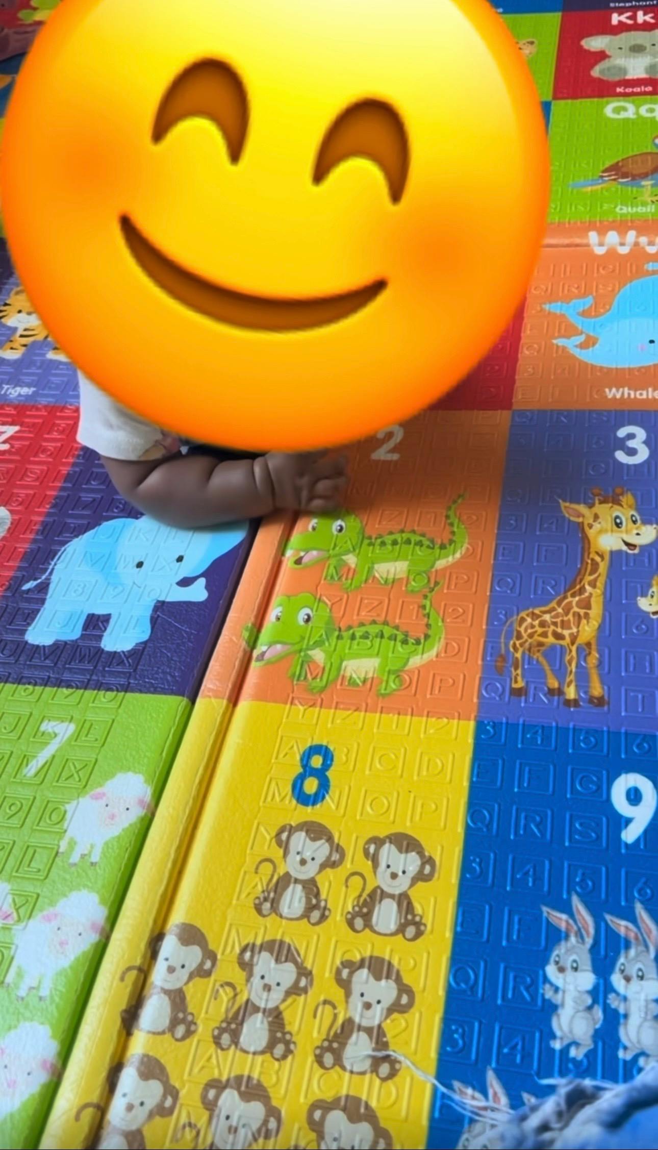 Child sitting on a colorful educational play mat with animal illustrations