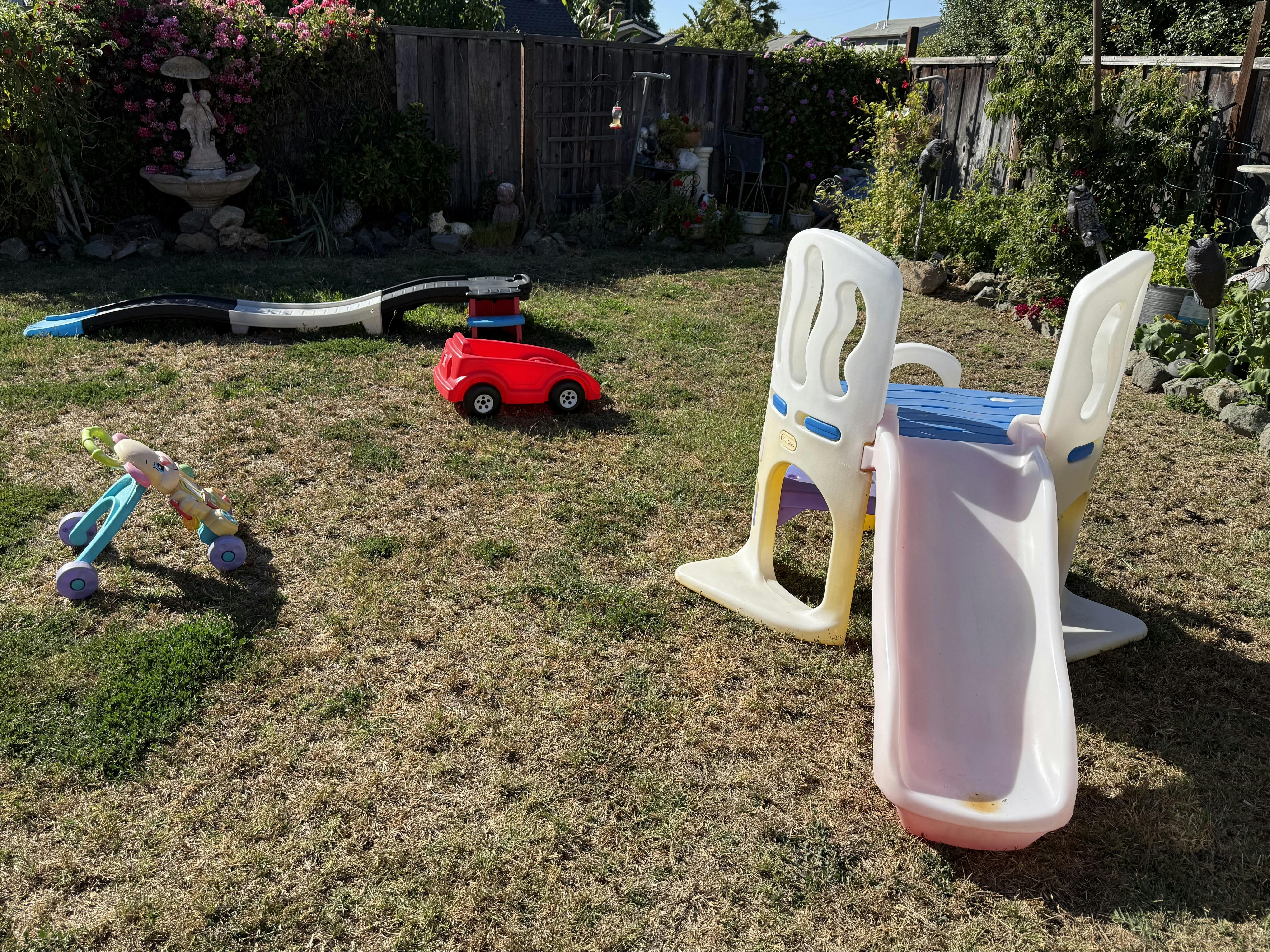 Plastic play equipment including a slide and small toy vehicles on a lawn