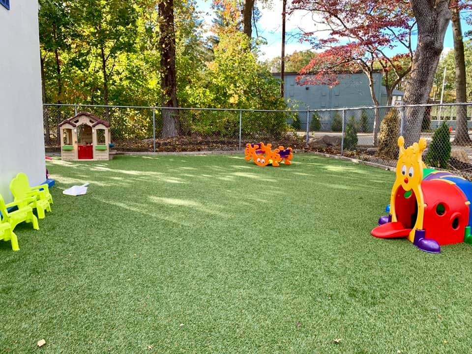 Outdoor play area with artificial turf, playhouse, and caterpillar tunnel