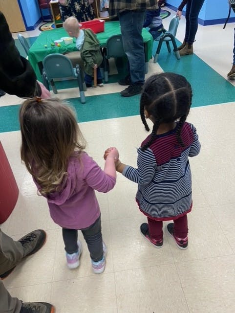 Two children holding hands in a classroom