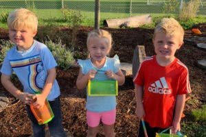 Three children holding containers outdoors
