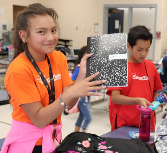 Child holding a speckled notebook, another child in background