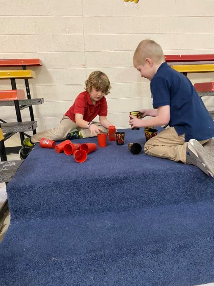 Two children playing with cups on a blue surface