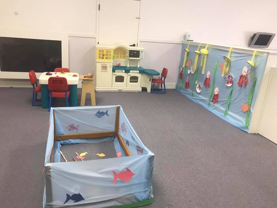 Playroom with a play kitchen, small table and chairs, and a sensory bin