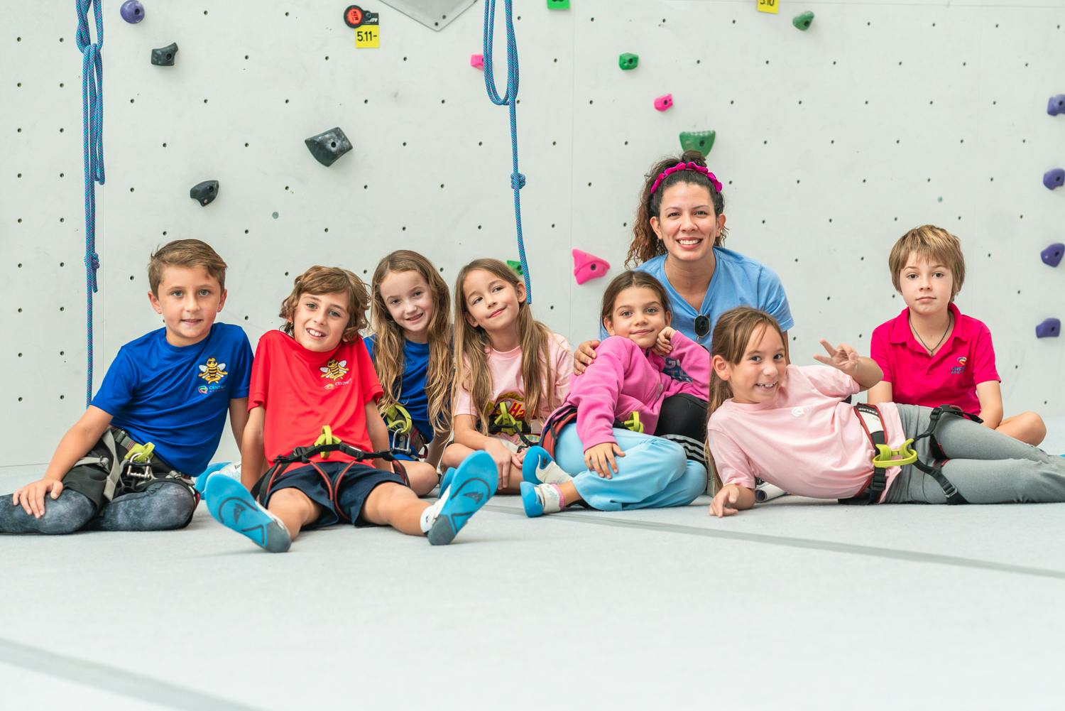 Adult and children sitting on floor in front of climbing wall