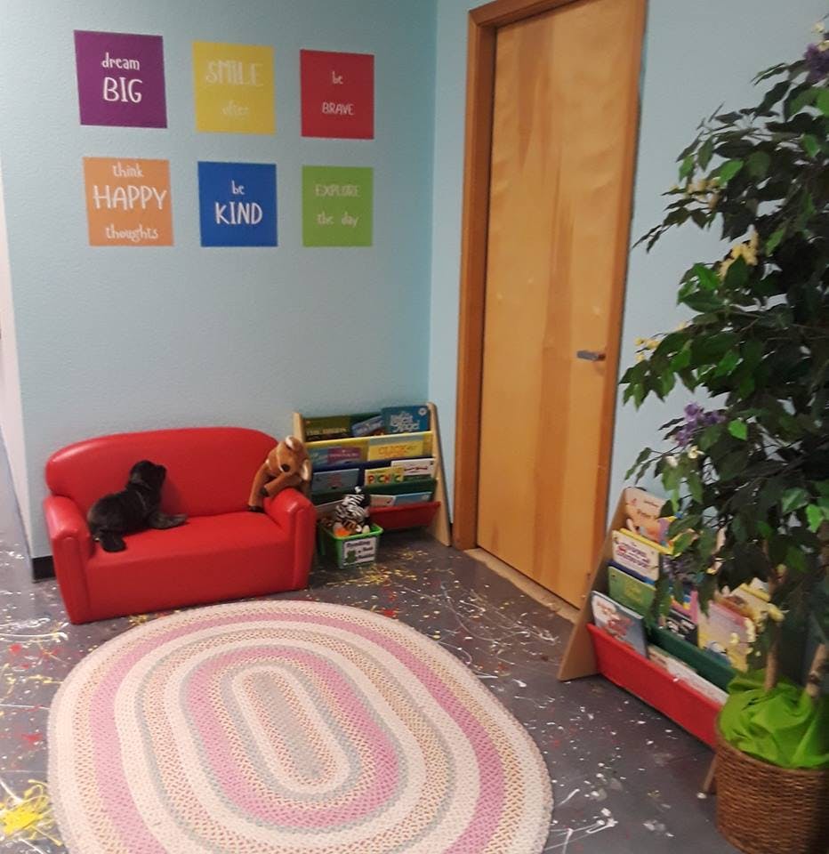 Red couch with a black cat, bookshelf, and rug in a room