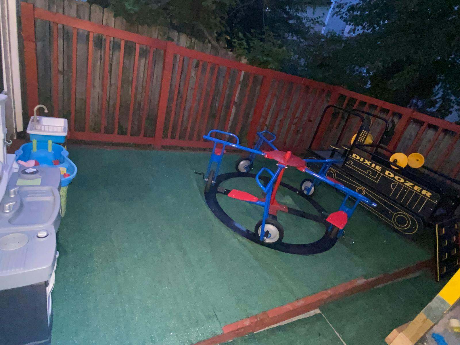 Playground equipment including a merry-go-round and toy vehicle in a yard