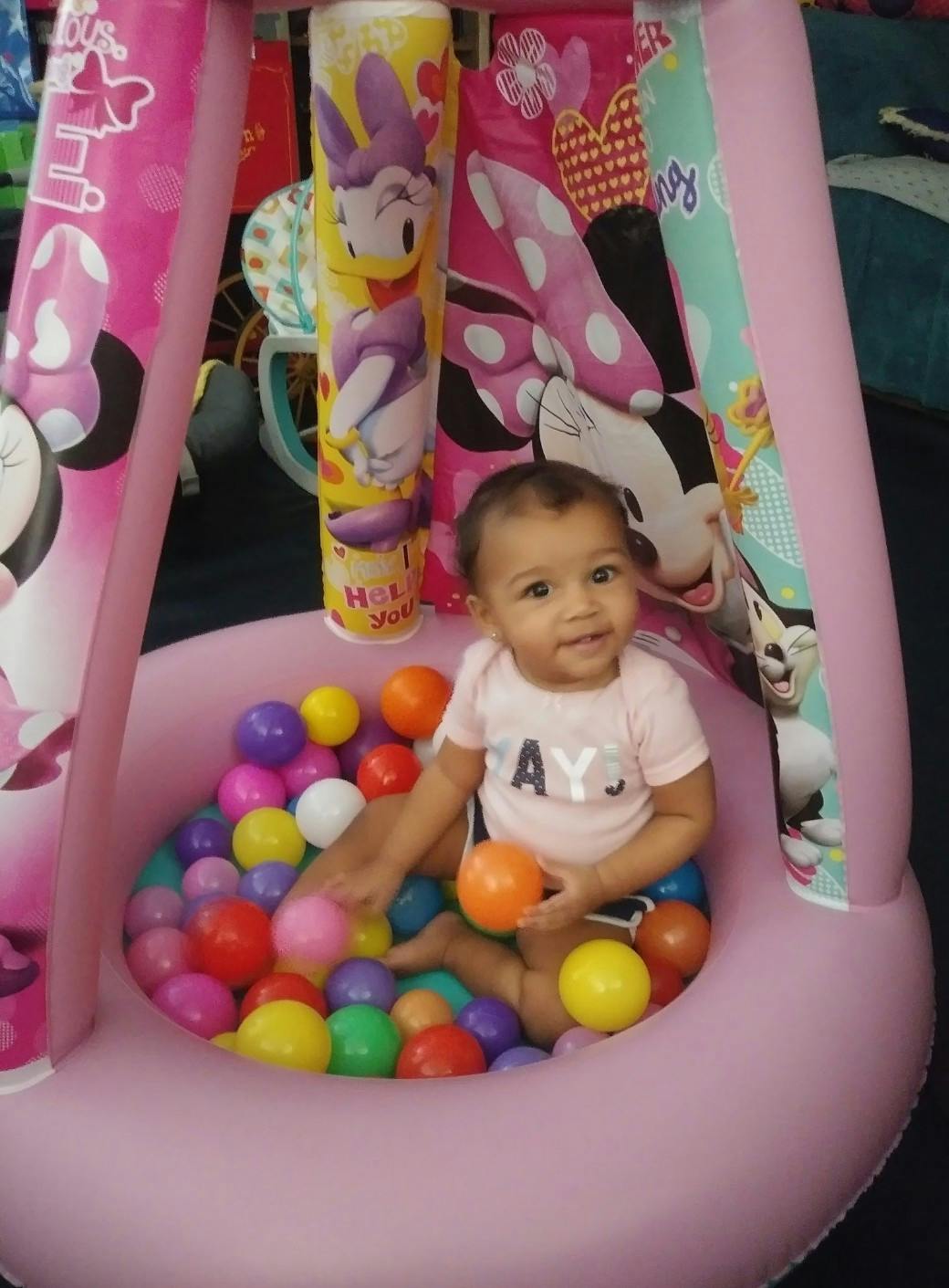Child sitting in a pink inflatable ball pit with colorful balls