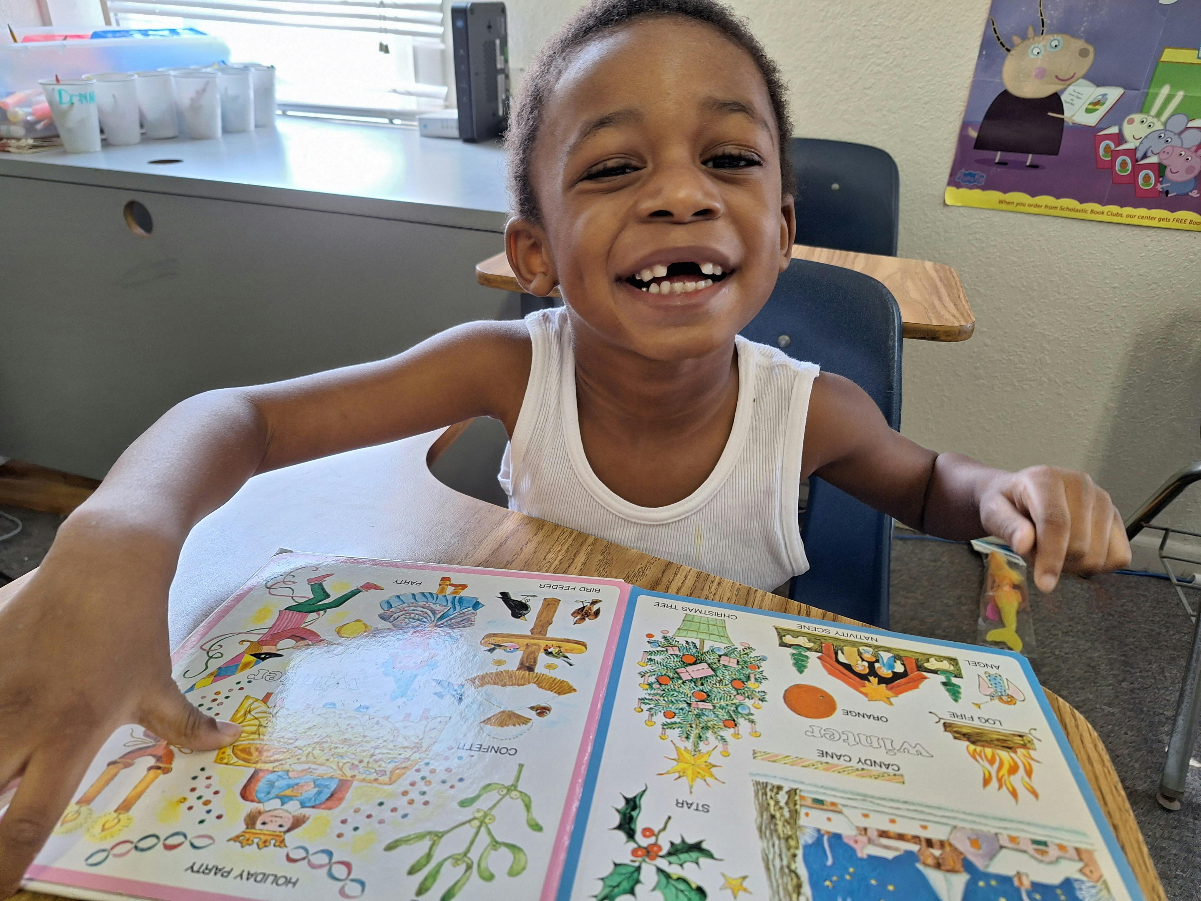 Child sitting at a desk with an open book