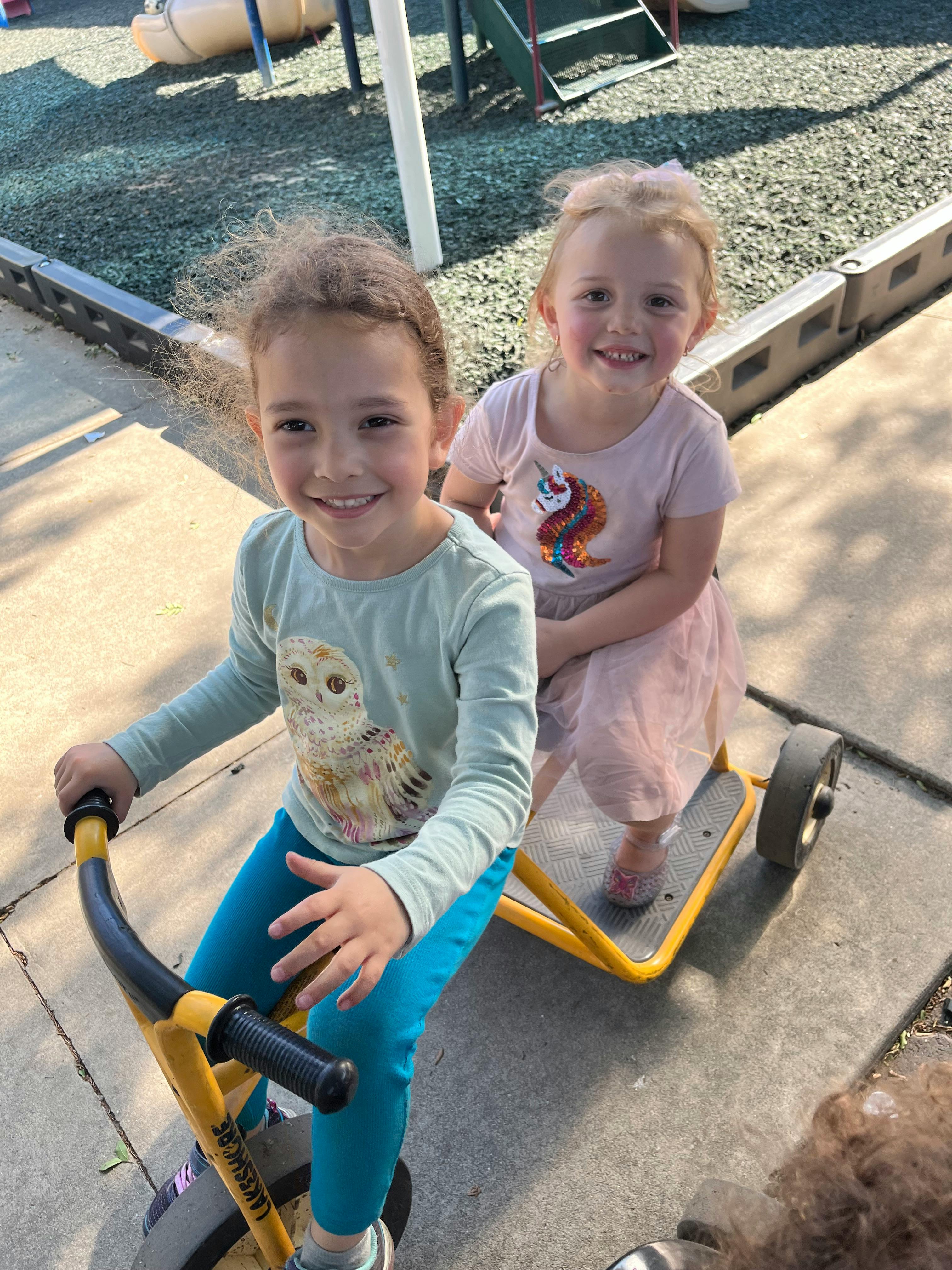 Two children on a yellow ride-on toy