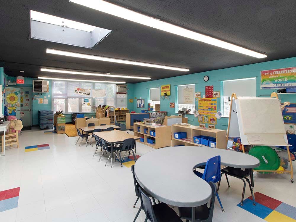 An empty preschool classroom with colorful walls and small tables and chairs